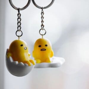 Two keychains with a yellow chick and an egg.